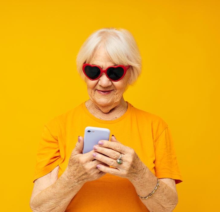 Elderly woman in dark glasses looking at a smart phone